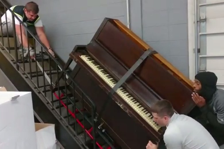 Guiding an upright piano down a staircase