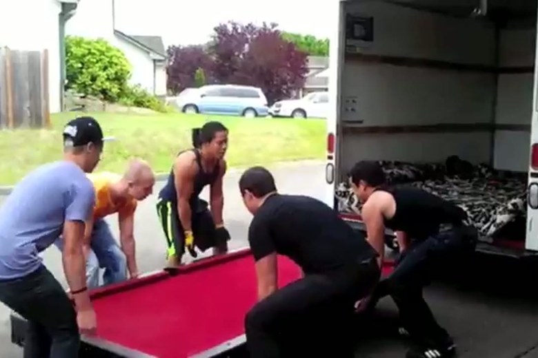A four-person crew moving a slate pool table